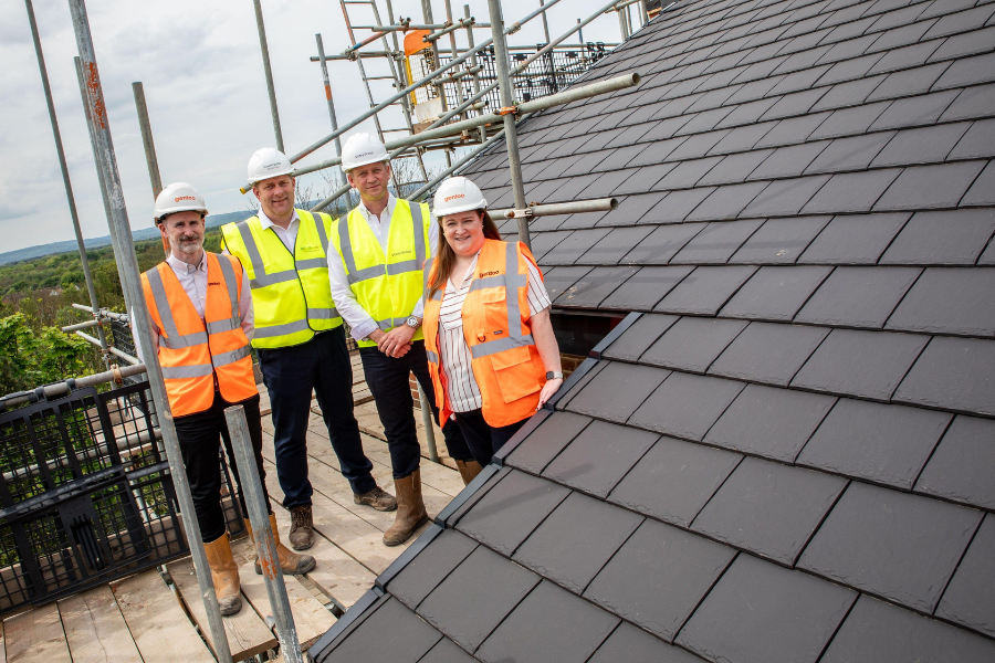 4 people stood on scaffolding next to roof tiles