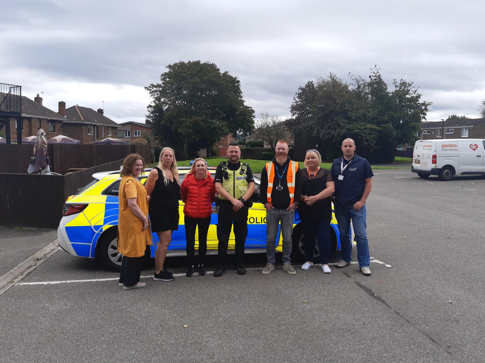 Group of people standing in front of a police car 