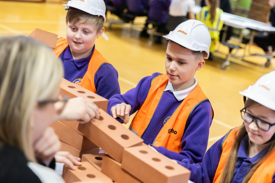Children in hi vis jackets and hard hats playing with bricks