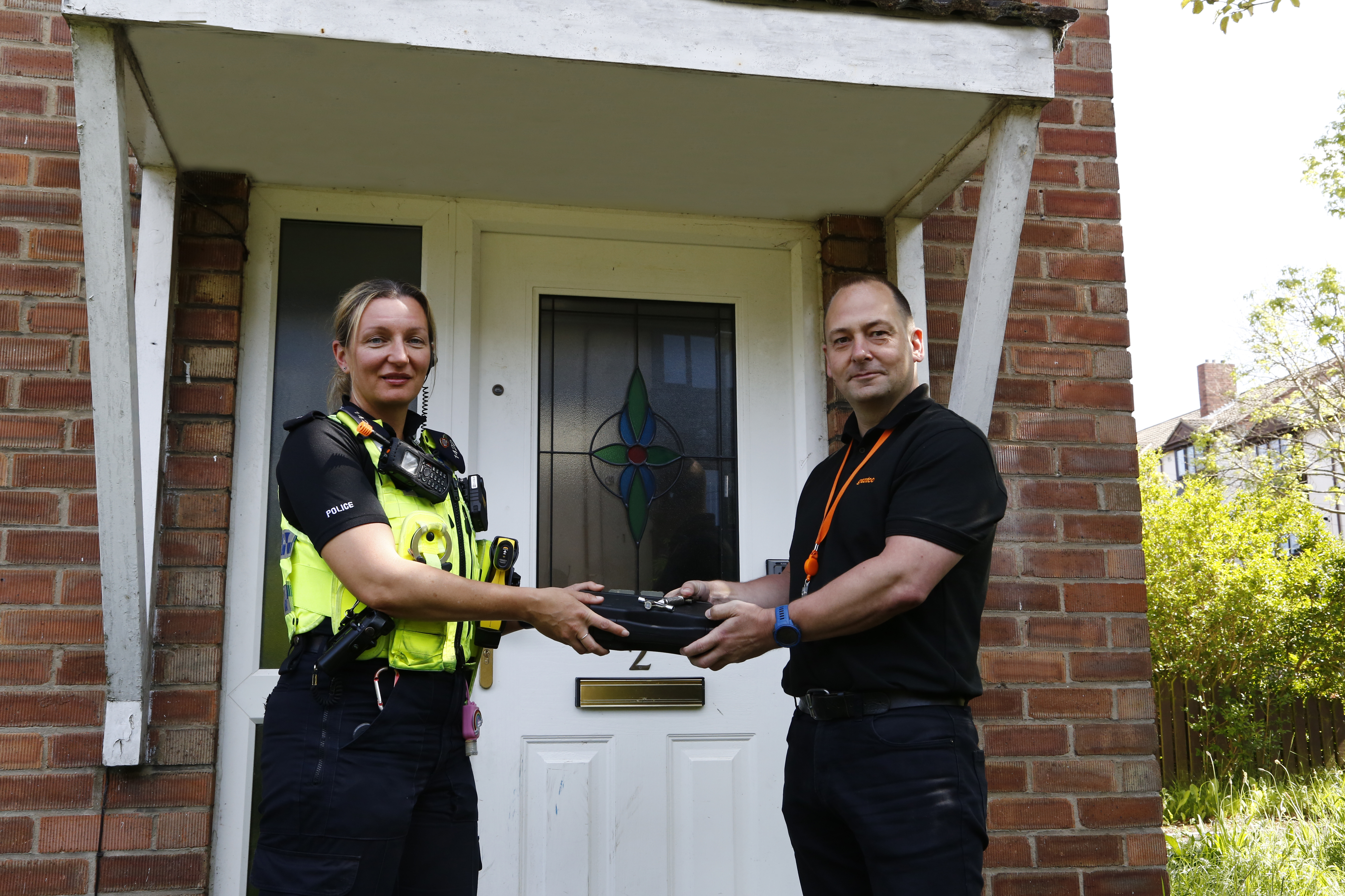 Two people standing in front of a door handing over a lock pulling kit