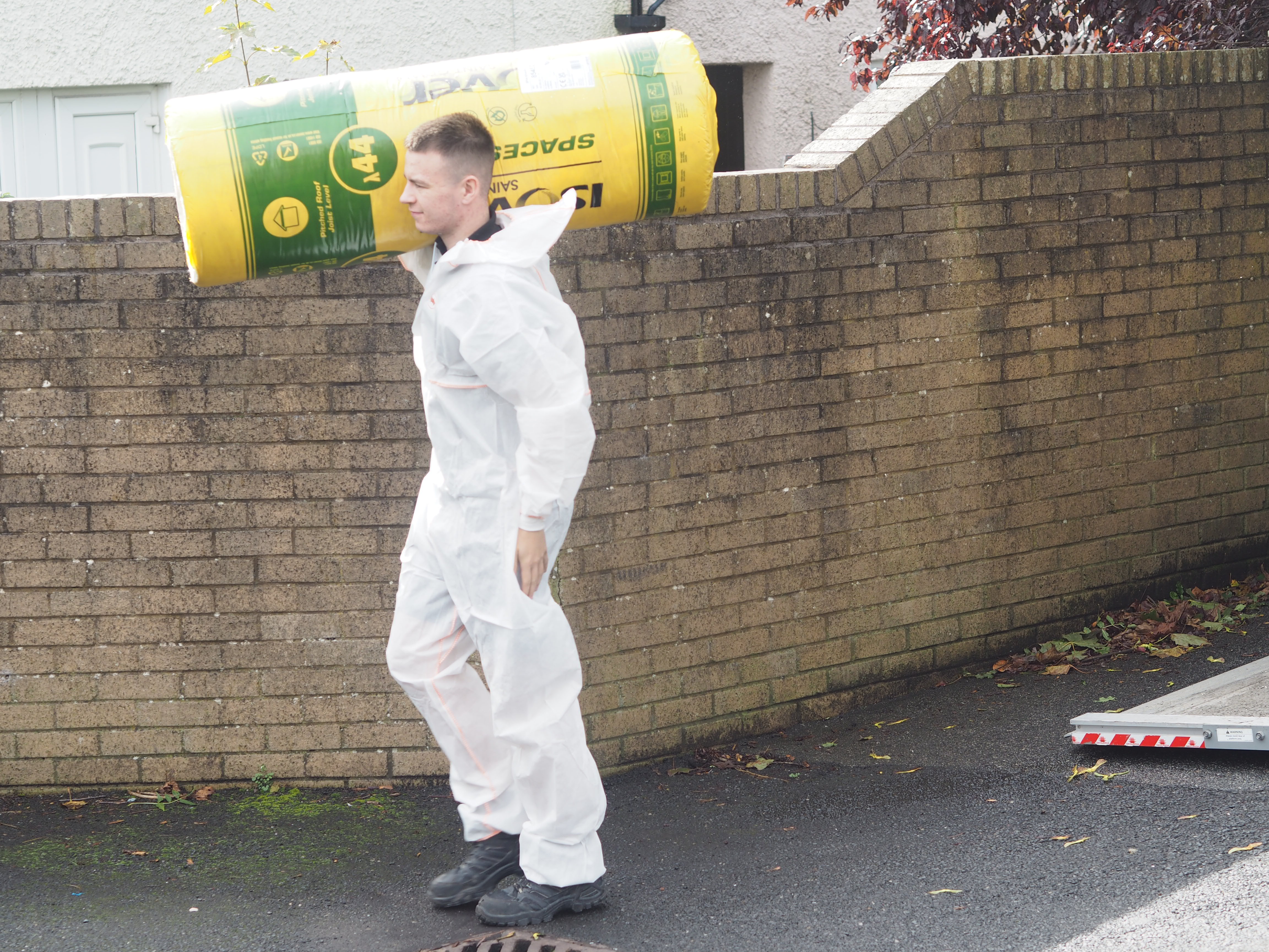 Person carrying large roll of loft insulation on shoulder
